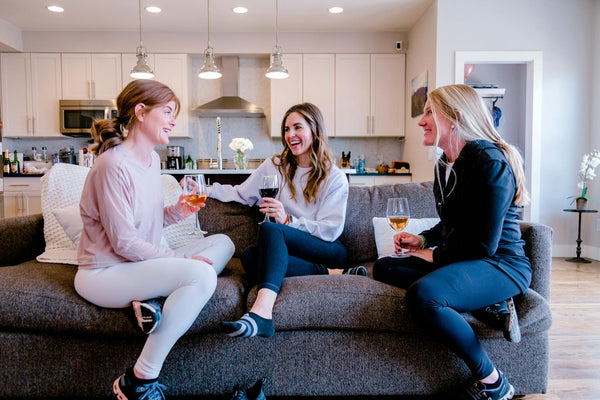 Three women laughing and talking while drinking wine in single-serve wine bottles
